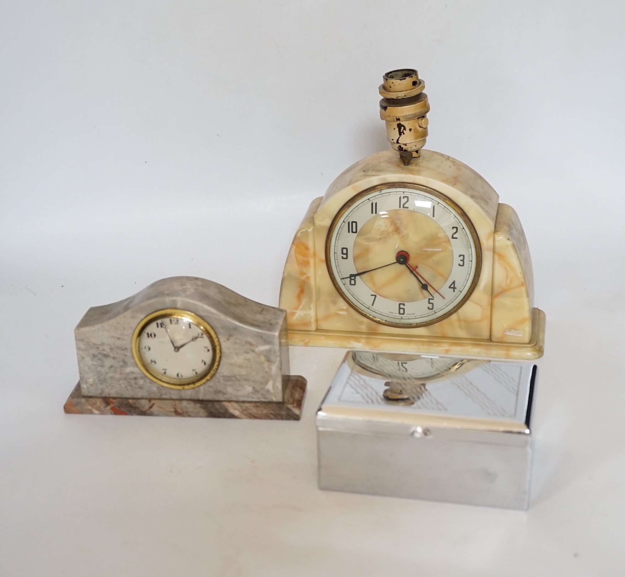 A black Bakelite box and similar clock desk stand, a faux marble clock, a marble clock, and a chrome box containing phenolic dominoes, desk stand 36cm wide (5)